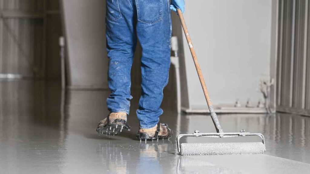Tradesperson mixing epoxy resin in a bucket before floor application